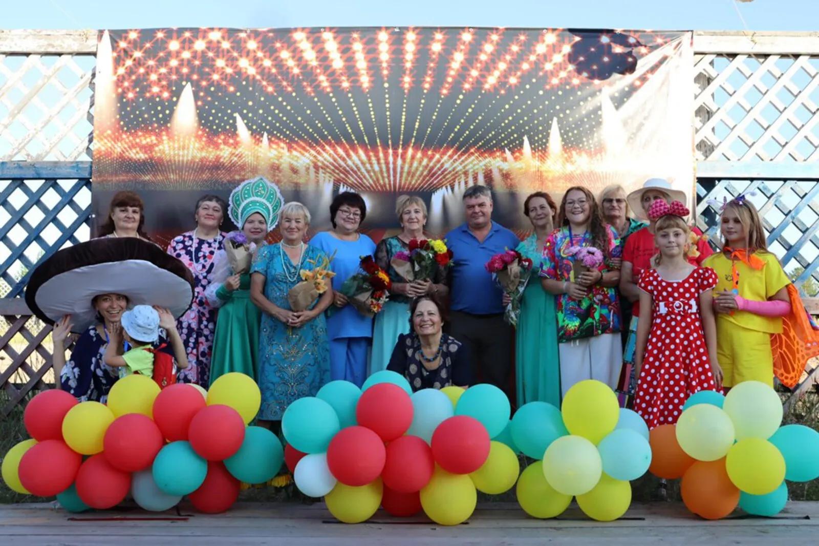 Участники фестиваля стоят на сцене с букетами